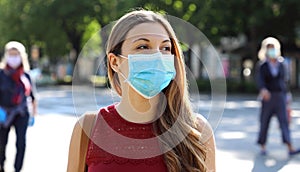 COVID-19 Social Distancing Woman in city street wearing surgical mask against disease virus SARS-CoV-2. Girl with face mask walks