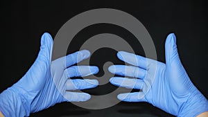 COVID-19 Two hands dressed in blue surgical gloves, stretched forward, fingers leaning towards each other, slightly apart, on a