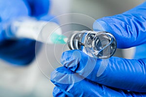 COVID-19 UK vaccine clinical trial concept,hands in blue gloves holding bottle vial