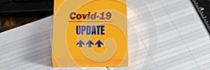 COVID-19 UPDATE text on yellow sticker on desktop background, banner format