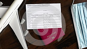 COVID-19 Vaccination Record Card on desk, coronavirus immunization certificate and tourist passport