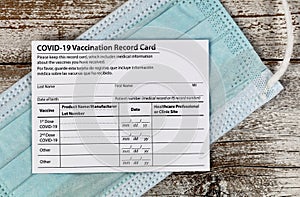 Covid 19 vaccination record card with facemask in close up view.  Individual record for use during the covid 19 coronavirus global