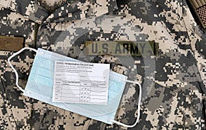 Covid 19 vaccination record card and personal facemask on US Army military uniform