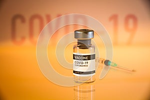 Covid-19 vaccine bottle and syringe on a yellow background