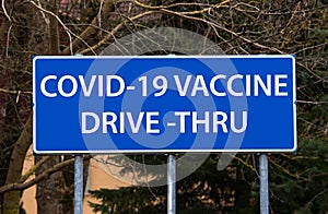 Covid-19 vaccine drive-thru concept. Blue road sign pointing to drive thru-vaccination site.