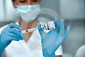 COVID-19 vaccine in researcher hands, female doctor holds syringe and bottle with vaccine for coronavirus cure.