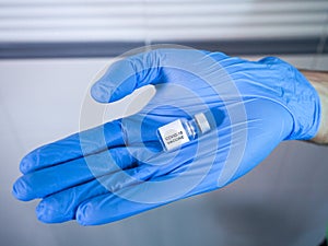 Covid-19 vaccine vial held by the gloved hand of a healthcare staff