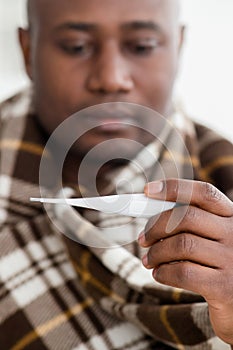 Covid-19 virus concept. Ill african american man looking at thermometer after measuring temperature, crop, closeup