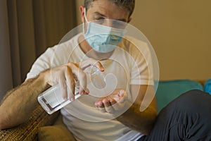 Covid-19 virus lockdown - sad and worried man  covered with medical mask washing hands with sanitizer gel in home quarantine