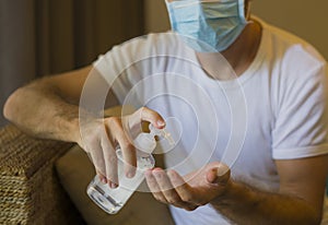 Covid-19 virus lockdown - sad and worried man  covered with medical mask washing hands with sanitizer gel in home quarantine