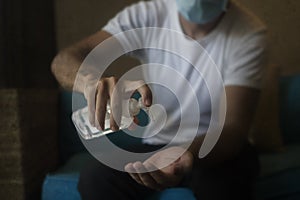 Covid-19 virus lockdown - sad and worried man  covered with medical mask washing hands with sanitizer gel in home quarantine