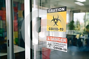 Covid-19 Warning signs stick on the glass door. Quarantine and outbreak alert signs of coronavirus outbreak control