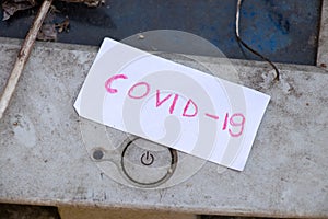 COVID-19 is written on a piece of paper and lies next to the turn off button on an old computer