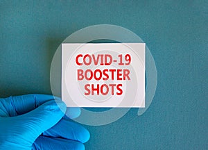 Covid-19 booster shots vaccine symbol. White note with words Covid-19 booster shots, beautiful blue background, doctor hand in photo