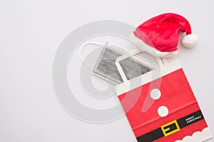 Covid-19 in Christmas festival celebration concept. Flat lay of red santa claus hat and protective face mask in gift bag