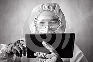 COVID-19 coronavirus concept, doctor in PPE suit uses digital tablet