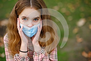 COVID-19 Coronavirus pandemic girl child in a city park wearing a mask protecting against the spread of the SARS-CoV-2 virus