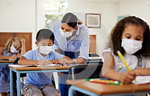 Covid, education and learning with a teacher wearing a mask and helping a male student in class during school. Young boy