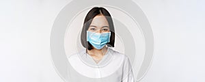 Covid and healthcare concept. Close up portrait of asian woman, office lady in face mask, smiling, using protection from