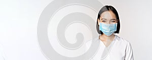 Covid and healthcare concept. Close up portrait of asian woman, office lady in face mask, smiling, using protection from