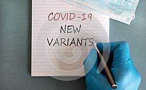 Covid-19 new variants symbol. Hand in blue glove with pen, white card. Concept words `Covid-19 new variants`. Medical face mask. photo