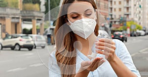 COVID-19 Pandemic Coronavirus Close up Woman with KN95 FFP2 Mask using Alcohol Gel Sanitizer Hands in City Street. Antiseptic, photo
