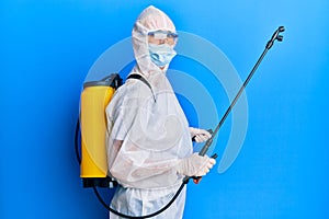 Covid specialist wearing decontamination protective suit and disinfectant spray, decontaminate and sanitize surface, standing over