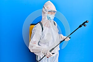 Covid specialist wearing decontamination protective suit and disinfectant spray, decontaminate and sanitize surface, standing over