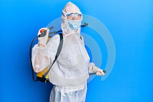 Covid specialist wearing decontamination protective suit and disinfectant spray, decontaminate and sanitize surface, standing over photo