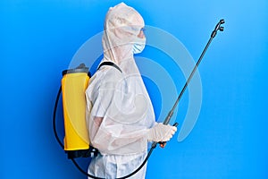 Covid specialist wearing decontamination protective suit and disinfectant spray, decontaminate and sanitize surface, standing over