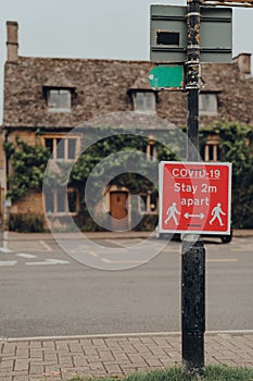 Covid-19 Stay 2 Metres Apart red sign on a street in Bourton-on-Water, Cotswolds, UK photo