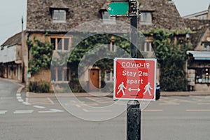 Covid-19 Stay 2 Metres Apart red sign on a street in Bourton-on-Water, Cotswolds, UK photo
