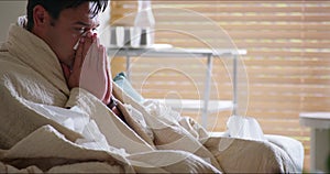 Covid, tissue and blanket with a sick man blowing his nose while at home on a sofa in the living room. Health, allergy