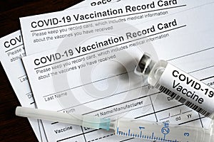 COVID-19 Vaccination Record Card on desk, top view of coronavirus immunization certificate photo