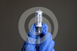 COVID-19 vaccine bottle and syringe for coronavirus cure in doctorÃ¢â¬â¢s gloved hands photo