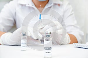 COVID-19 vaccine in researcher hands, female doctor holds syringe and bottle with vaccine for coronavirus cure. Concept of corona