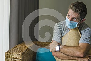 Covid-19 virus lockdown - sad and worried man in medical mask thinking and feeling scared in quarantine following stay at home photo