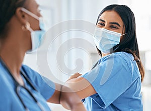 Covid, women and doctors elbow greeting in surgical mask at hospital or clinic during the pandemic. Teamwork, healthcare