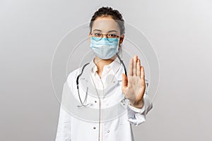 Covid19, coronavirus, healthcare and doctors concept. Serious asian female doctor in medical mask, with stethoscope and