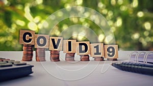 COVID19 text written on wooden blocks with downward stack of coins in vintage background