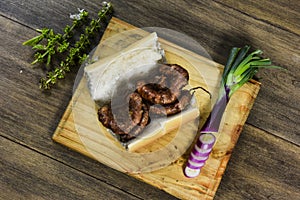 Cow bowels presented on a wooden board with ingredients, ready to grill