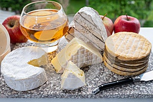 Cow cheeses of Normandy - camembert, livarot, neufchatel, pont l`eveque and glass of apple cider drink with houses of Etretat