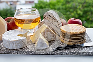 Cow cheeses of Normandy - camembert, livarot, neufchatel, pont l`eveque and glass of apple cider drink with houses of Etretat