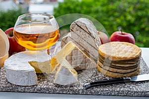 Cow cheeses of Normandy - camembert, livarot, neufchatel, pont l`eveque and glass of apple cider drink with houses of Etretat