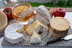 Cow cheeses of Normandy - camembert, livarot, neufchatel, pont l`eveque and glass of apple cider drink with houses of Etretat