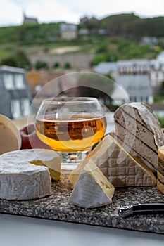 Cow cheeses of Normandy - camembert, livarot, neufchatel, pont l`eveque and glass of apple cider drink with houses of Etretat