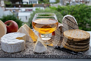 Cow cheeses of Normandy - camembert, livarot, neufchatel, pont l`eveque and glass of apple cider drink with houses of Etretat