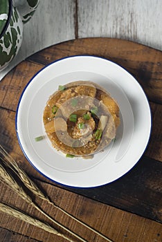 Cow skin meat cooked with spicy peanut sauce with onion leaves as garnish.