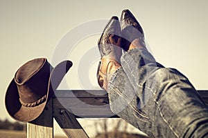 Cowboy boots and hat with feet up resting with legs crossed