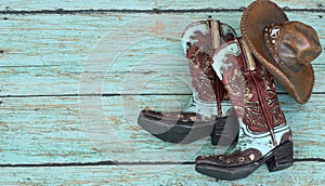 Cowboy boots and hat on a teal background